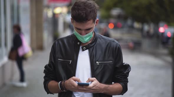 A young man with a cool hairstyle wearing a black jacket, a white t-shirt and a green protective Cov