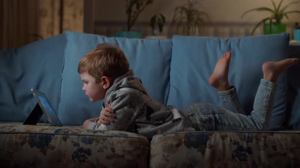 Kid using tablet computer on couch