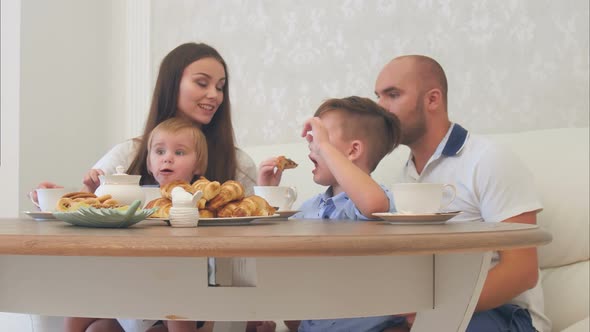 Happy Young Family Enjoying Tea with Sweets at Restaurant or Cafe or Home