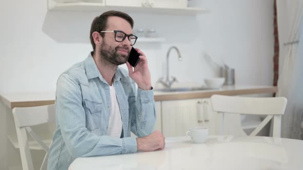 Cheerful Beard Young Man Talking on Smartphone in Office