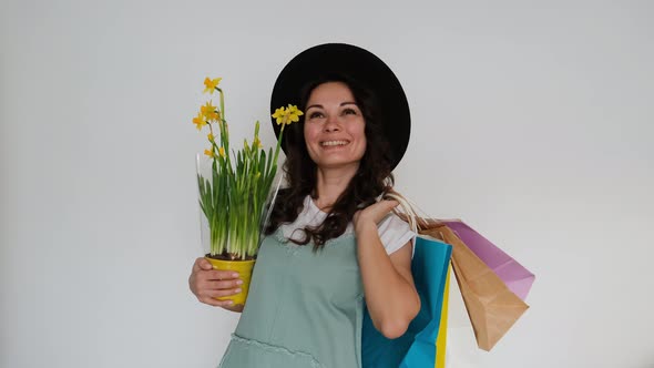 The Girl Happily Makes Purchases with Packages and Flowers