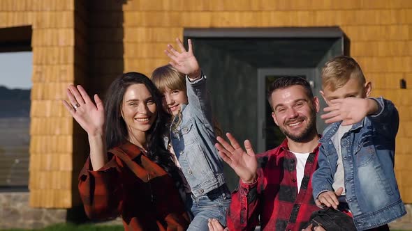 Happy Joyful Modern Family Which Posing on Camera Near Beautiful House and Waving Hands