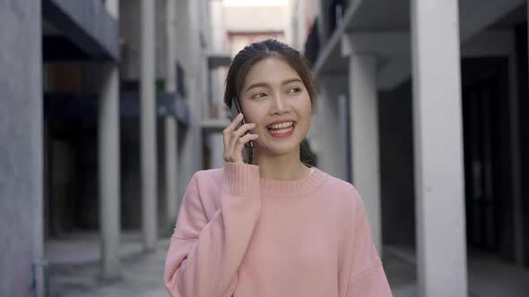 Young Asian woman using smartphone for talking while walking in the city traveling in holidays.