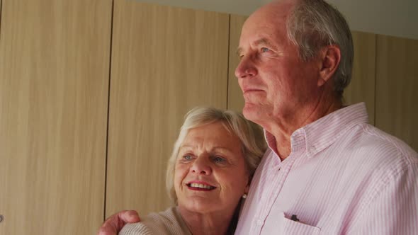 Senior couple in social distancing hugging each other in retirement house