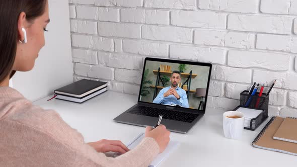 Woman student study online by conference video call laptop, writes in notebook