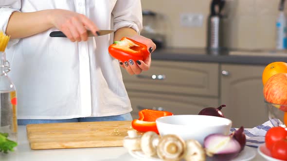 Close-up of a Young Woman Cutting Vegetables in the Kitchen