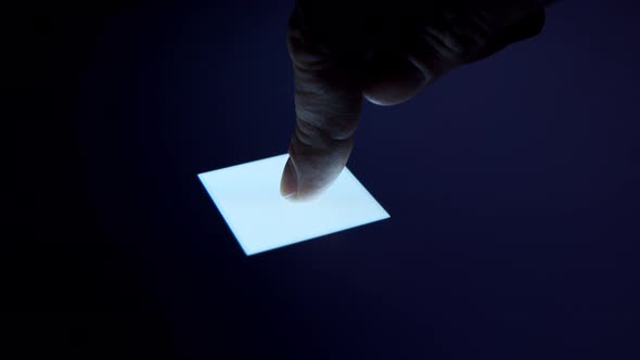 Human finger is pressing a digital button on a glowing touchscreen.