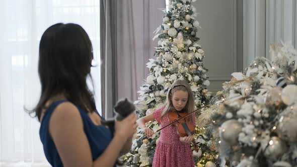 Girl Plays Violin While Mom Holds Kitten in Xmas