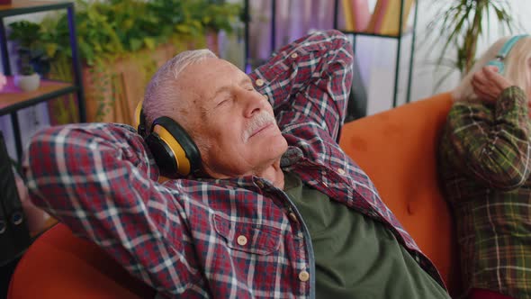 Happy Senior Family Grandparents Man Woman in Headphones Listening Music Relaxing on Couch at Home