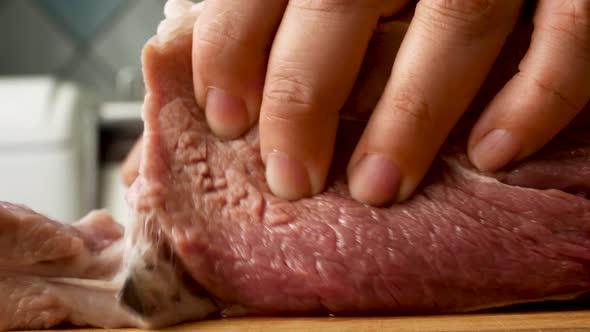 Female Hands Cut Raw Pork Meat with a Knife on a Wooden Board in the Kitchen