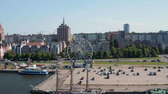 Slide and Pan Shot of Waterfront with Moored Ships and Ferris Wheel at Large Parking Lot