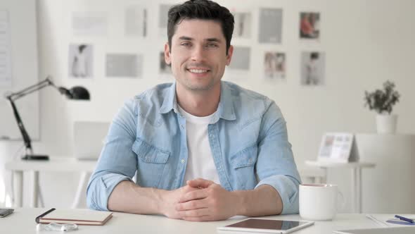 Successful Smiling Casual Young Man Sitting at Workplace