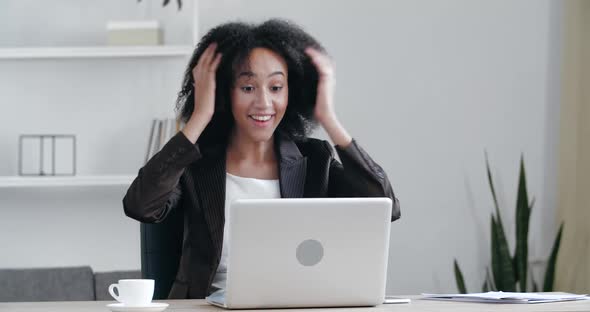 Successful African Young Woman Sits at Table Uses Laptop Read E-mails Online Home Office, Gets Good