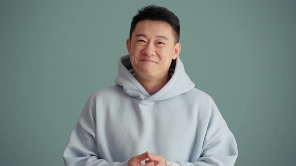Positive Asian man wearing hoodie positively shaking his head