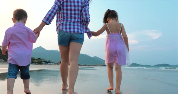 Young Family, Mother and Children Are Walking Along the Coast. Happy Family Walking on Sea Coast.