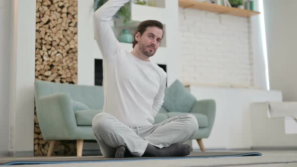 Young Man Doing Stretches on Yoga Mat at Home