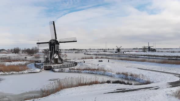 Snow covered Dutch windmills canals and polder land, cold winter aerial view