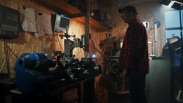 Male Master Engineer Manages Cnc Drilling Machine in a Dark Workshop Garage