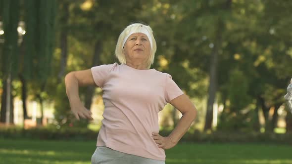 Female Pensioners Stretching in Park Before Training, Warming Up Upper Body