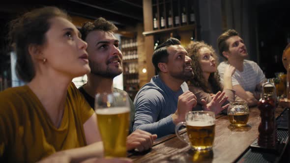 Group of friends cheering to soccer match in the pub. Shot with RED helium camera in 8K. 