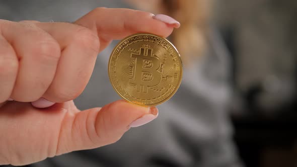 Closeup of a Golden Bitcoin Coin in the Hands of a Young Business Woman