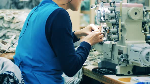 Factory Worker Is Sewing Fabric with a Machine and Checking It