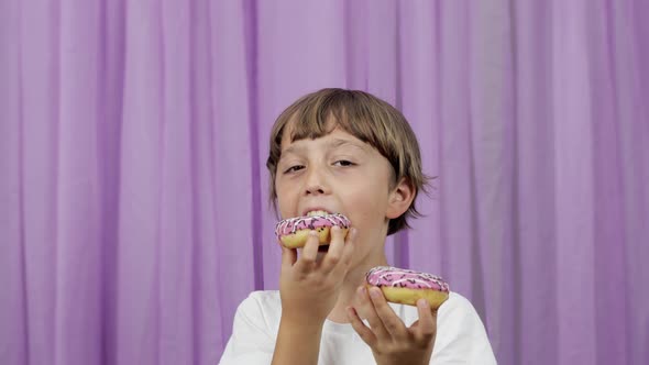 Boy of 9 Years Old is Biting a Donut on a Purple Background