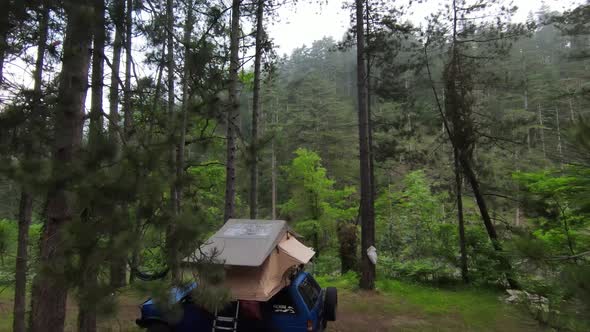 A Car Roof Top Tent for Camping on the Roof Rack of an Offroad Car in a Forest on a Misty Cloudy