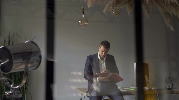 behind the glass a man looks at a folder with documents in the office