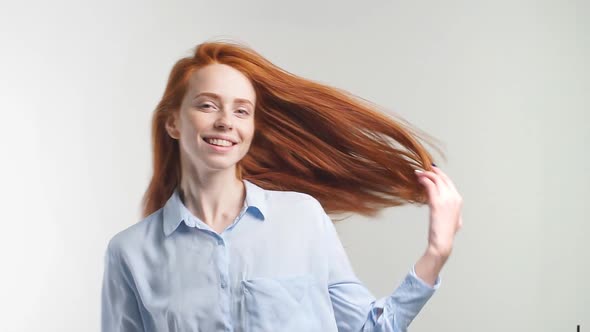 Pretty Cheerful Redhead Girl with Flying Curly Hair Smiling Laughing Looking at Camera Over White