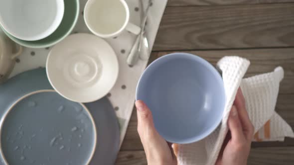 Top View Of A Young Woman In The Kitchen Wipes Clean Dishes With A Dry Towel On A Kitchen Table