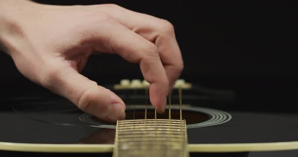 Close up of fingers strumming strings of guitar