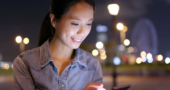 Asian woman use of mobile phone in the city at night 