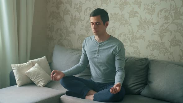 A Man Sitting on the Couch Meditates