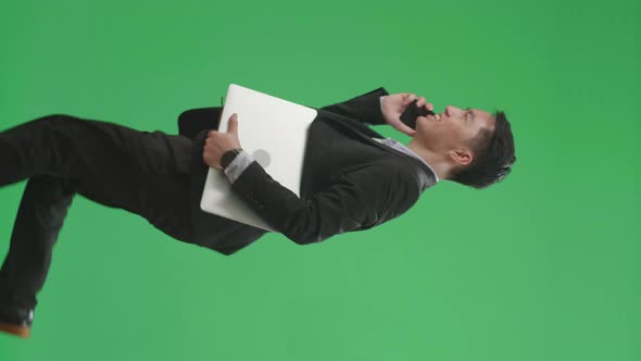 Side View Of Asian Business Man Talking On Mobile Phone While Walk And Run On Green Screen