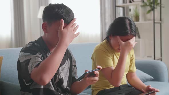 Asian Children Playing Video Games On Mobile Phone And Disappointed At Home