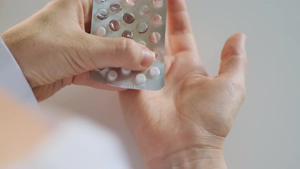 Patient or Doctor Squeezes or Removes Small White Tablets From Blister Pack Into Palm of Hand