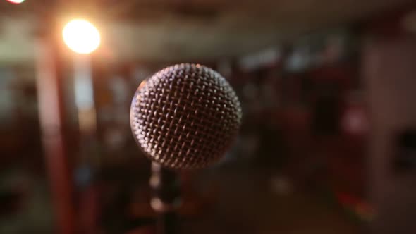 View of microphone on stage facing empty auditorium. Colorful spotlights