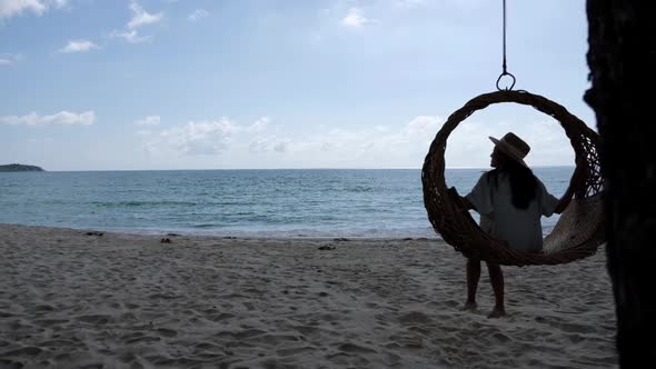 Slow motion of a beautiful young asian woman sitting on swing by the sea