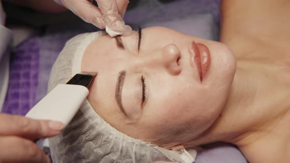 Woman Cleansing Facial in Spa Salon