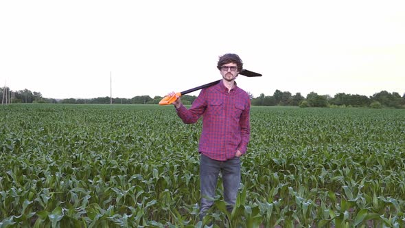 The farmer holds a shovel in his hand on an agricultural field, harvest time.