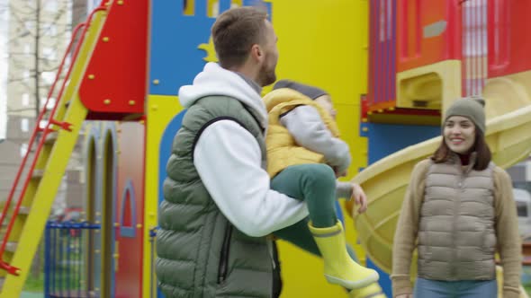 Loving Caucasian Dad and Son Spinning Around Together at Playground