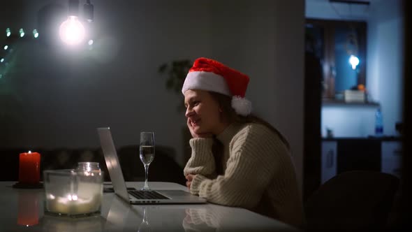 Woman in a Santa Hat Taking a Video Call on a Laptop with Friends
