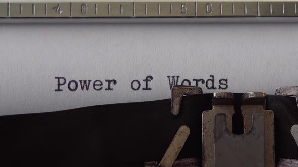 Typing phrase Power of Words on retro typewriter. Close up.