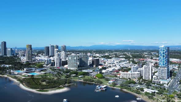 Towering buildings and aquatic centre built on the foreshore amongst a urban city sprawl. Panning dr