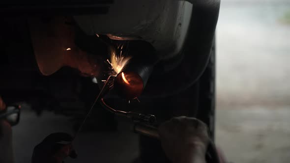 blacksmith welder works with metal steel and iron using a welding machine, bright sparks and flashes