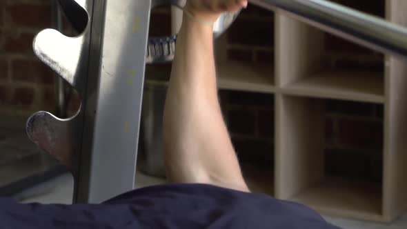 Muscly man in home gym exercising smith machine bench press