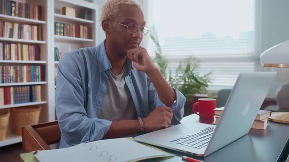 Focused Young African American Man Uses Laptop to Study at Home