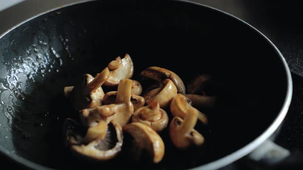 Chef Flips Mushrooms in a Frying Pan.