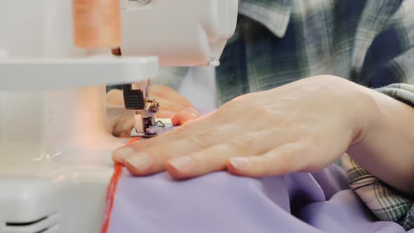 Close up of woman fingers sew on sewing machine. Sewing concept